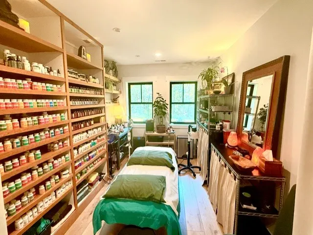 Image of the body work room with table, surrounded by shelves full of herbs and supplements